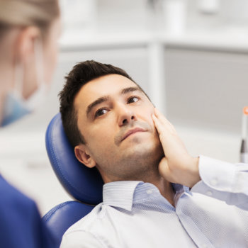 a man with a toothache sitting in a dental chair