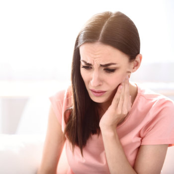 brunette suffering from severe toothache touching her cheek
