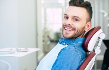 Happy, smiling young man sitting in a dental chair